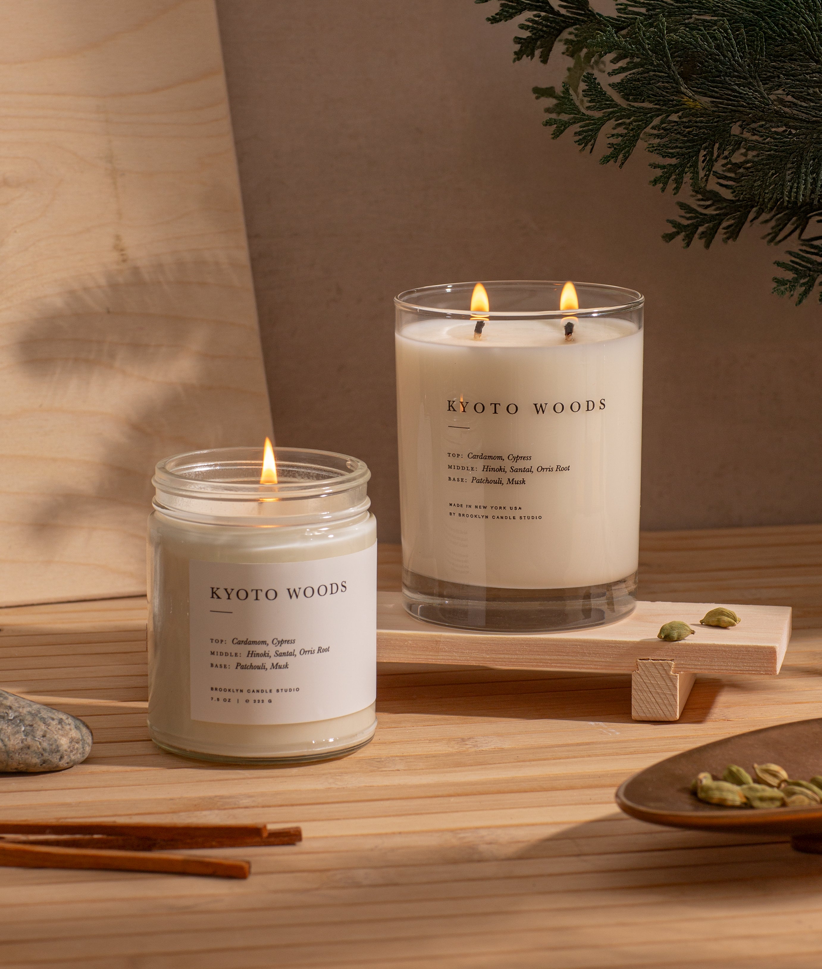 Two Kyoto Woods candles on a wooden surface with a neutral background