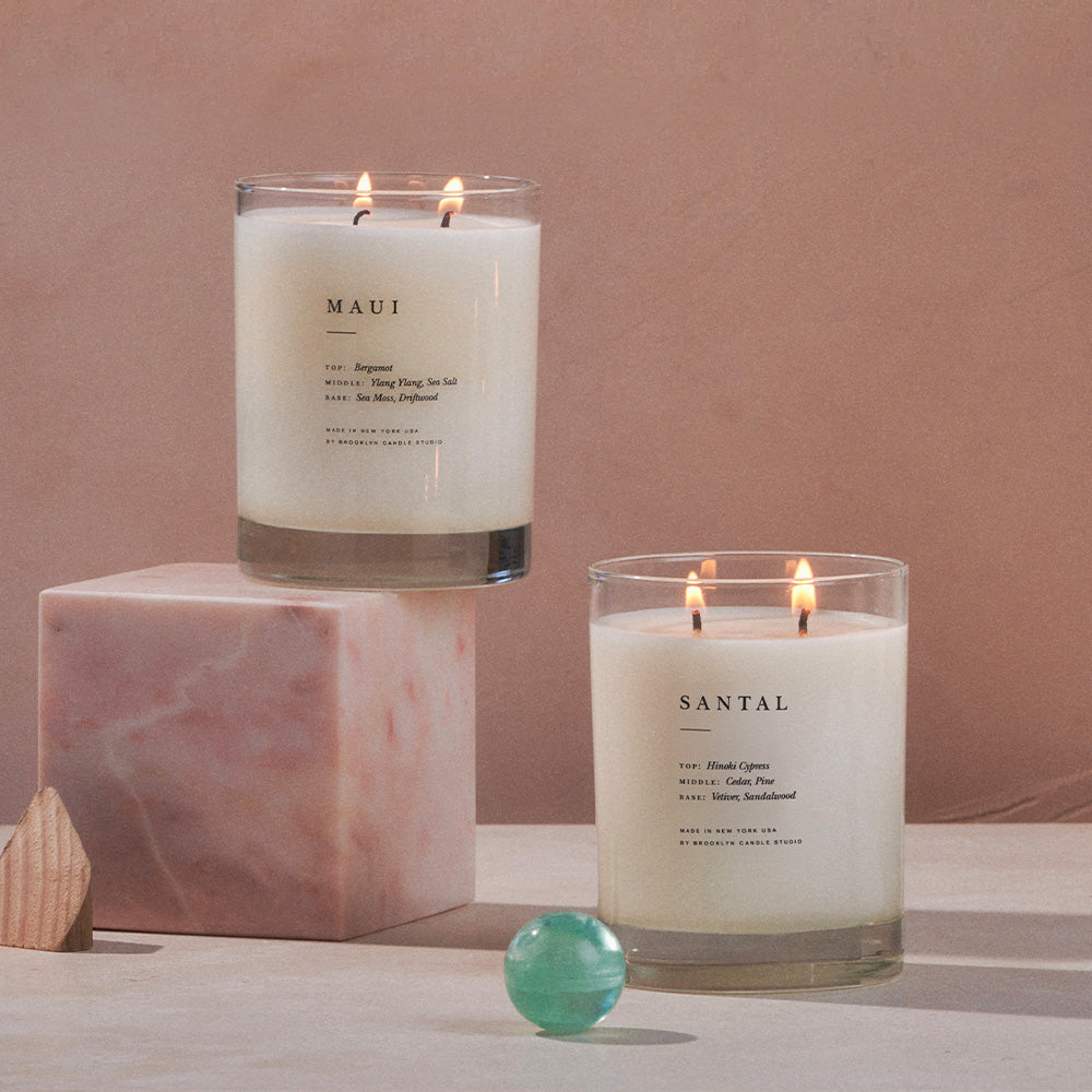 Two lit candles labeled 'MAUI' and 'SANTAL' on a neutral background