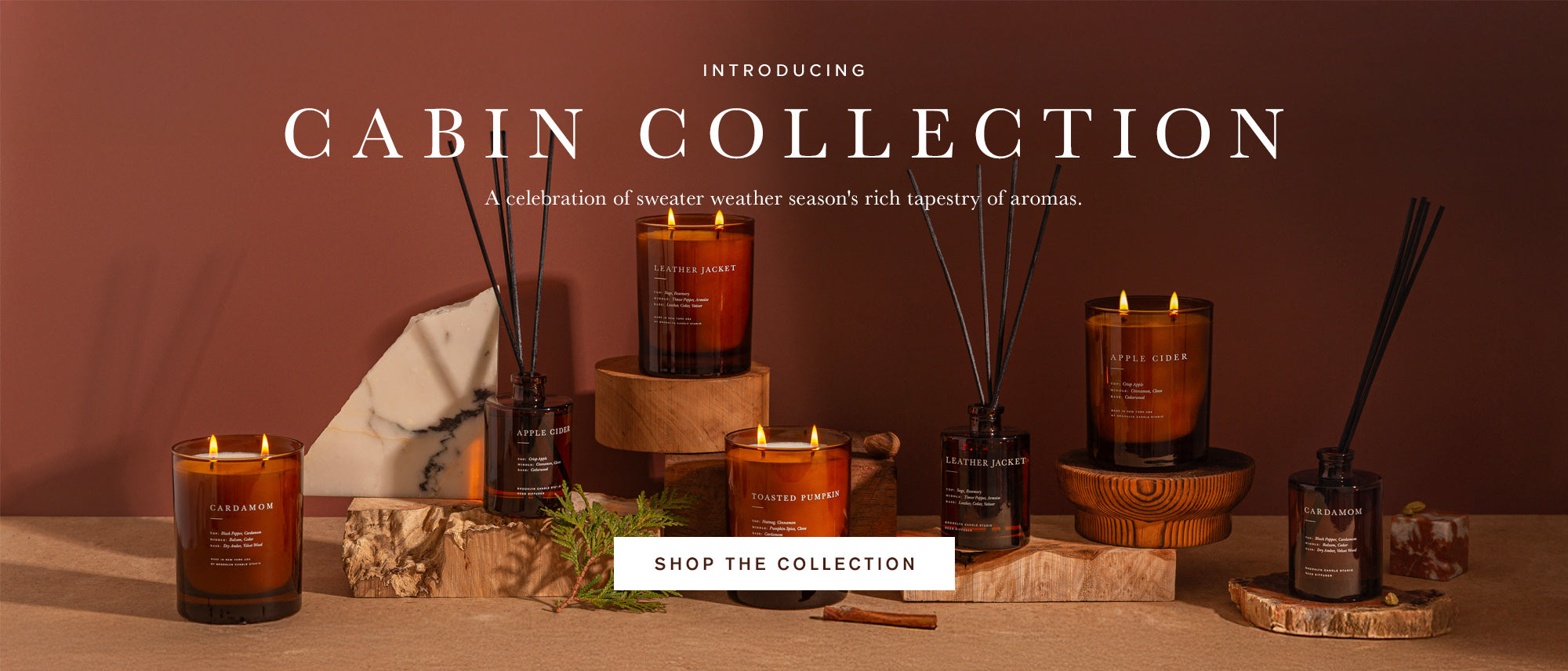 Cabin Collection featuring amber glass candles and reed diffusers with large text reading 'INTRODUCING CABIN COLLECTION' and a 'SHOP THE COLLECTION' button